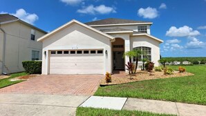 A single-story house with a garage, a front yard with landscaping, and a clear blue sky. - Ov3131 - Highlands Reserve - 5 Bed 3 Baths Villa (Davenport)