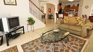 A living room with a sofa, coffee table, TV, and a staircase leading to another room. - Ov3131 - Highlands Reserve - 5 Bed 3 Baths Villa (Davenport)