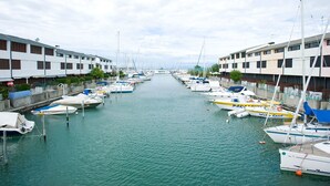 A marina with boats docked along a canal, flanked by buildings with balconies. - Isola Terramare (Lignano Sabbiadoro)