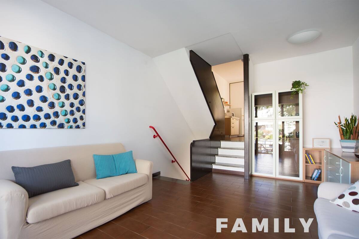 Una sala de estar moderna con un sofá, una escalera y un ventanal grande.