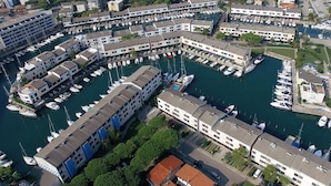 An aerial view of a marina with boats docked, surrounded by multi-story buildings with balconies. - Isola Terramare (Lignano Sabbiadoro)