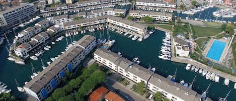 An aerial view of a marina with boats docked, surrounded by multi-story buildings with balconies.