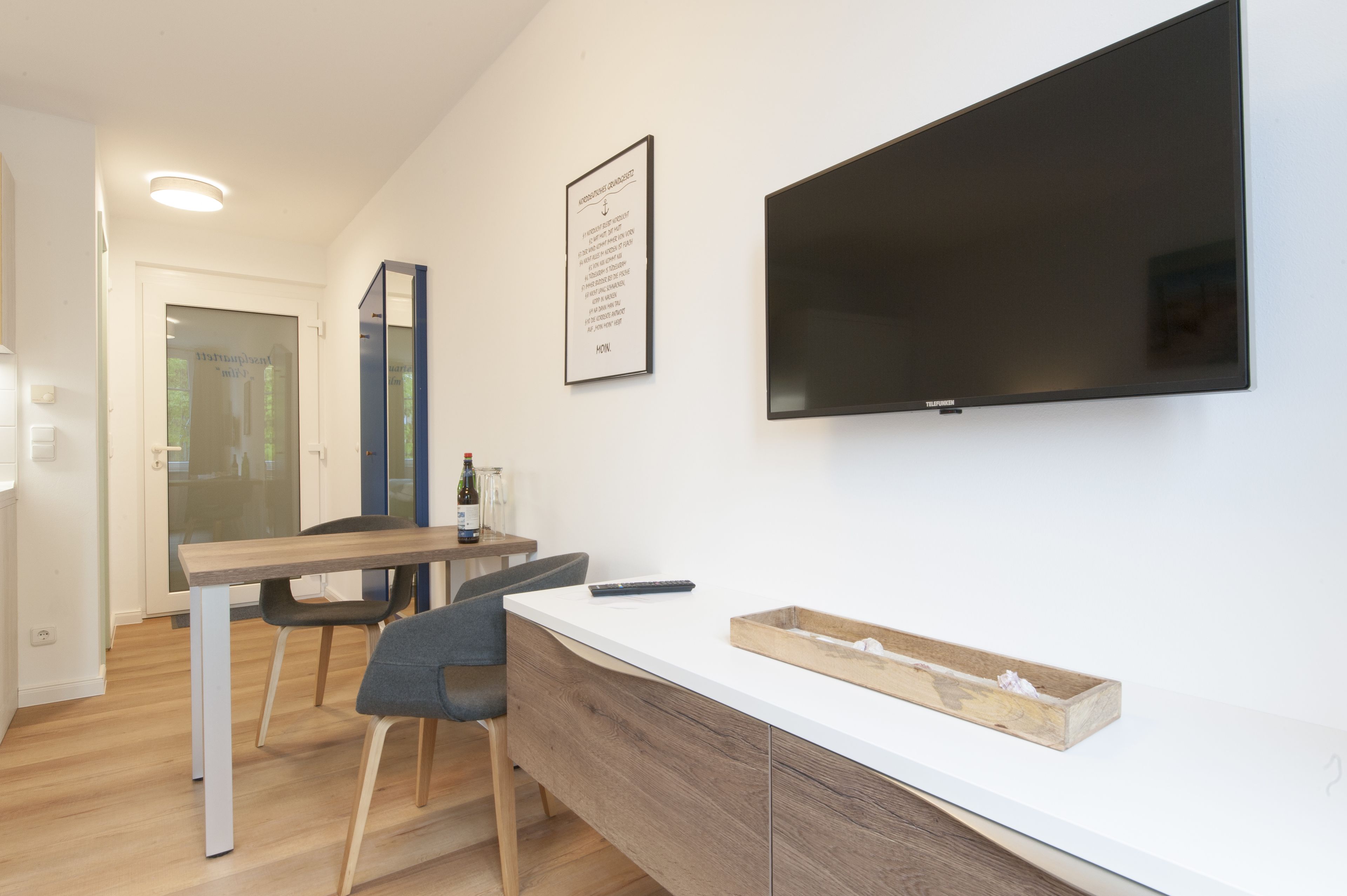 A modern kitchen with a wooden countertop, a built-in oven, and a large flat-screen TV mounted on the wall.