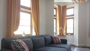 Een moderne woonkamer met een grijze bank, twee kussens met een patroon en een witte salontafel.
