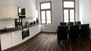 Een moderne keuken met witte kasten, een houten aanrecht en een eethoek met zwarte stoelen.
