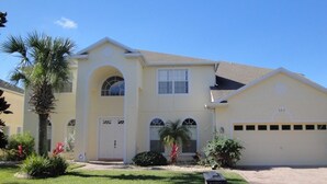 A two-story house with a front entrance, a garage, and a well-maintained lawn. - Ov3125 - Highlands Reserve - 6 Bed 4 Baths Villa (Davenport)