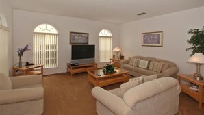 A living room with a sofa, armchairs, a coffee table, a TV, and two lamps. - Ov3125 - Highlands Reserve - 6 Bed 4 Baths Villa (Davenport)