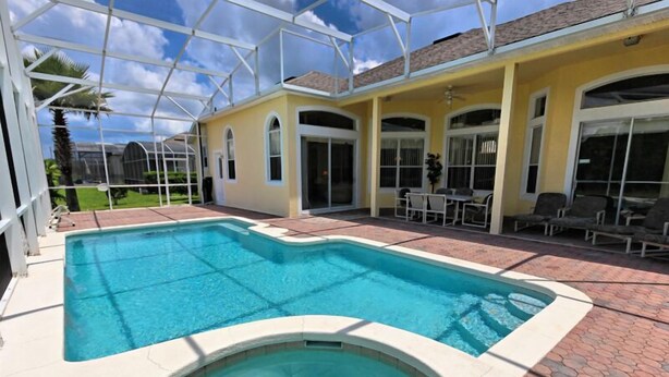 A covered swimming pool with a patio area, a hot tub, and outdoor furniture.