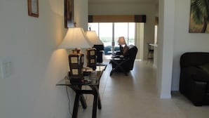 Una sala de estar con una mesa de centro de vidrio, dos lámparas, un sofá y una silla.