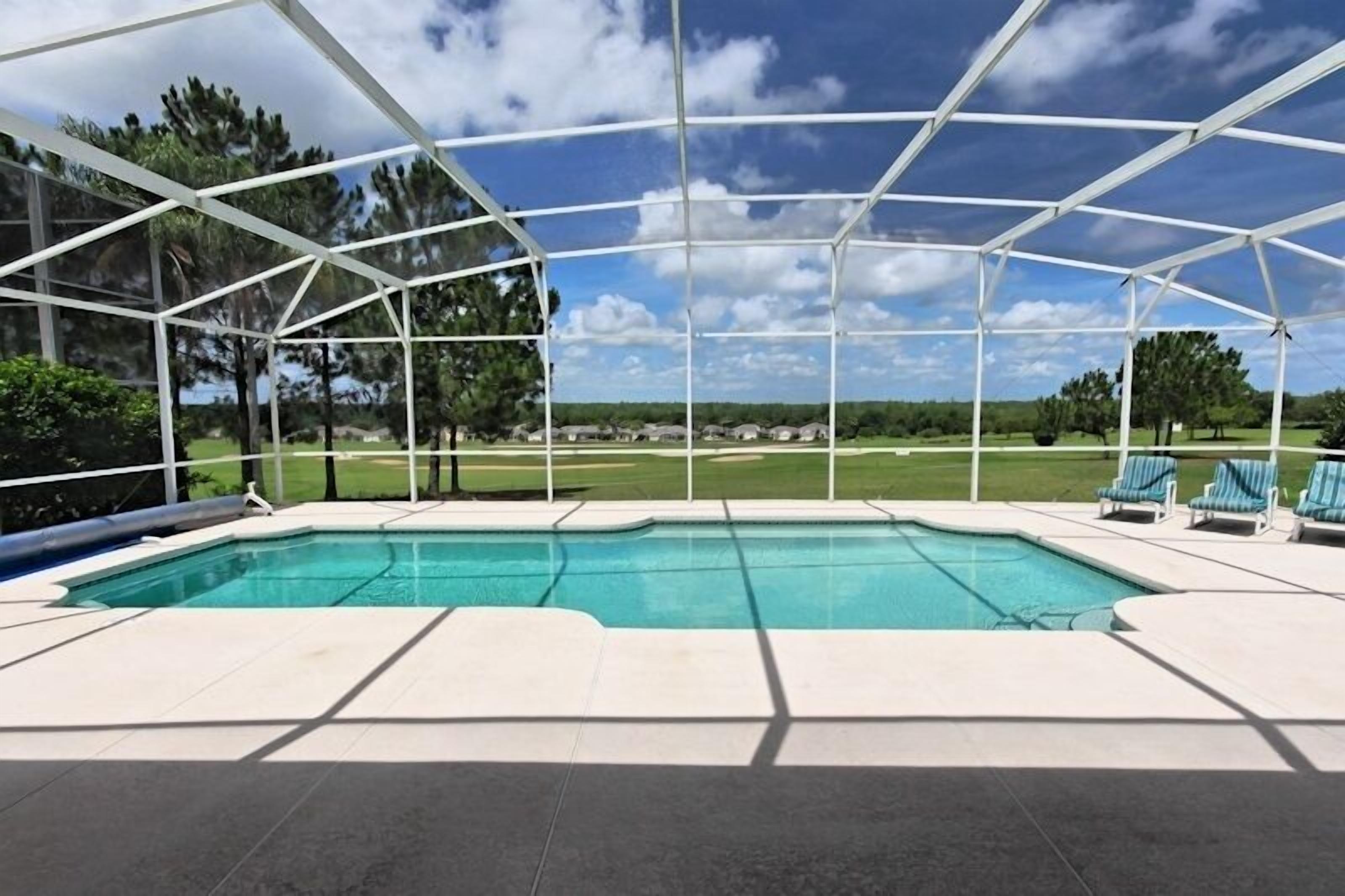 A covered swimming pool with a view of a golf course.