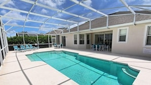 Una piscina cubierta al aire libre con sillas y mesas de descanso, rodeada por un edificio con grandes ventanales.
