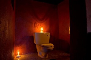 A toilet with a lit candle in a dimly lit room.