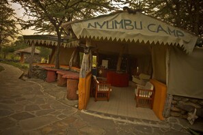 A rustic outdoor seating area with a canopy labeled "NYLIMBU CAMP".