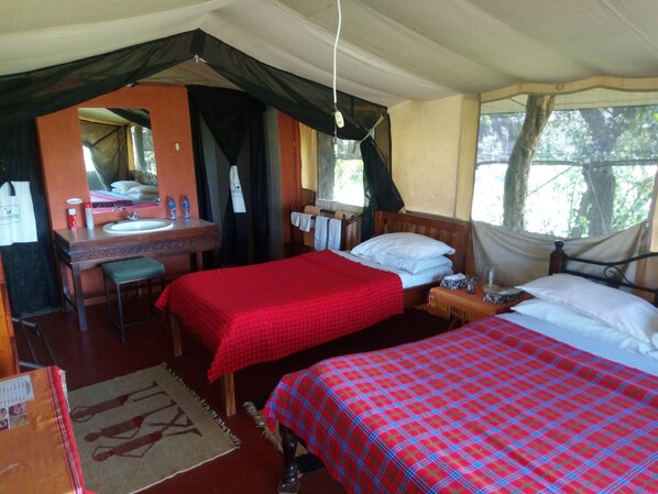 A room with two beds, a desk, a mirror, and a window with a view of trees.