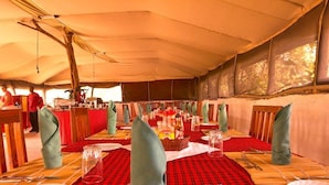 Une longue table à manger, dressée avec des nappes rouges et blanches, des sets de table en bambou et des serviettes vertes.