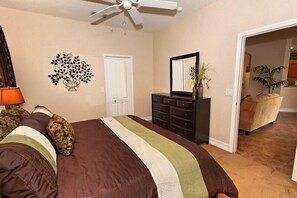 Un dormitorio con cama, cómoda y ventilador de techo.