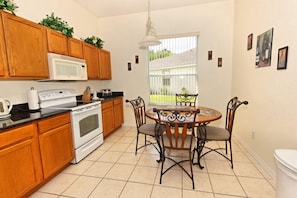 Enjoy meals in this kitchen with a dining table and chairs, a stove, and a window with an outside view.