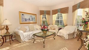 Una habitación con una mesa de centro de vidrio, dos sofás, un cuadro en la pared y una ventana con cortinas.