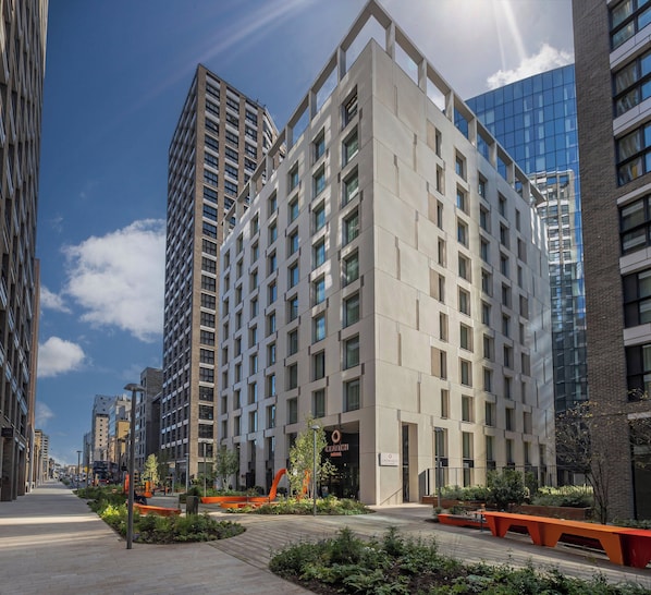 A modern hotel with a clean, geometric facade, large windows, and a well-maintained outdoor area with seating and plants. - Clayton Hotel City of London, Tower Bridge (London)