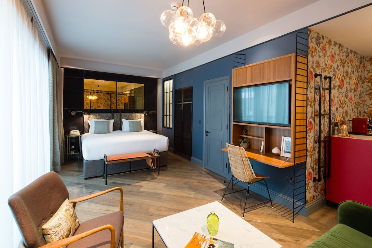 A modern hotel room with a bed, desk, chair, and a TV.