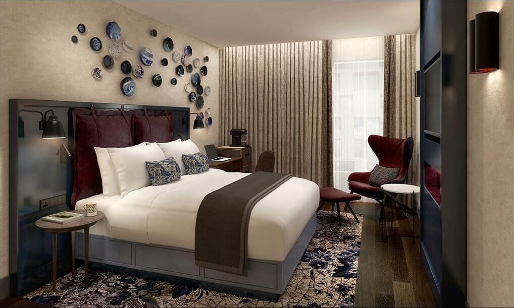 A modern hotel room with a large bed, a desk, a chair, and a TV.