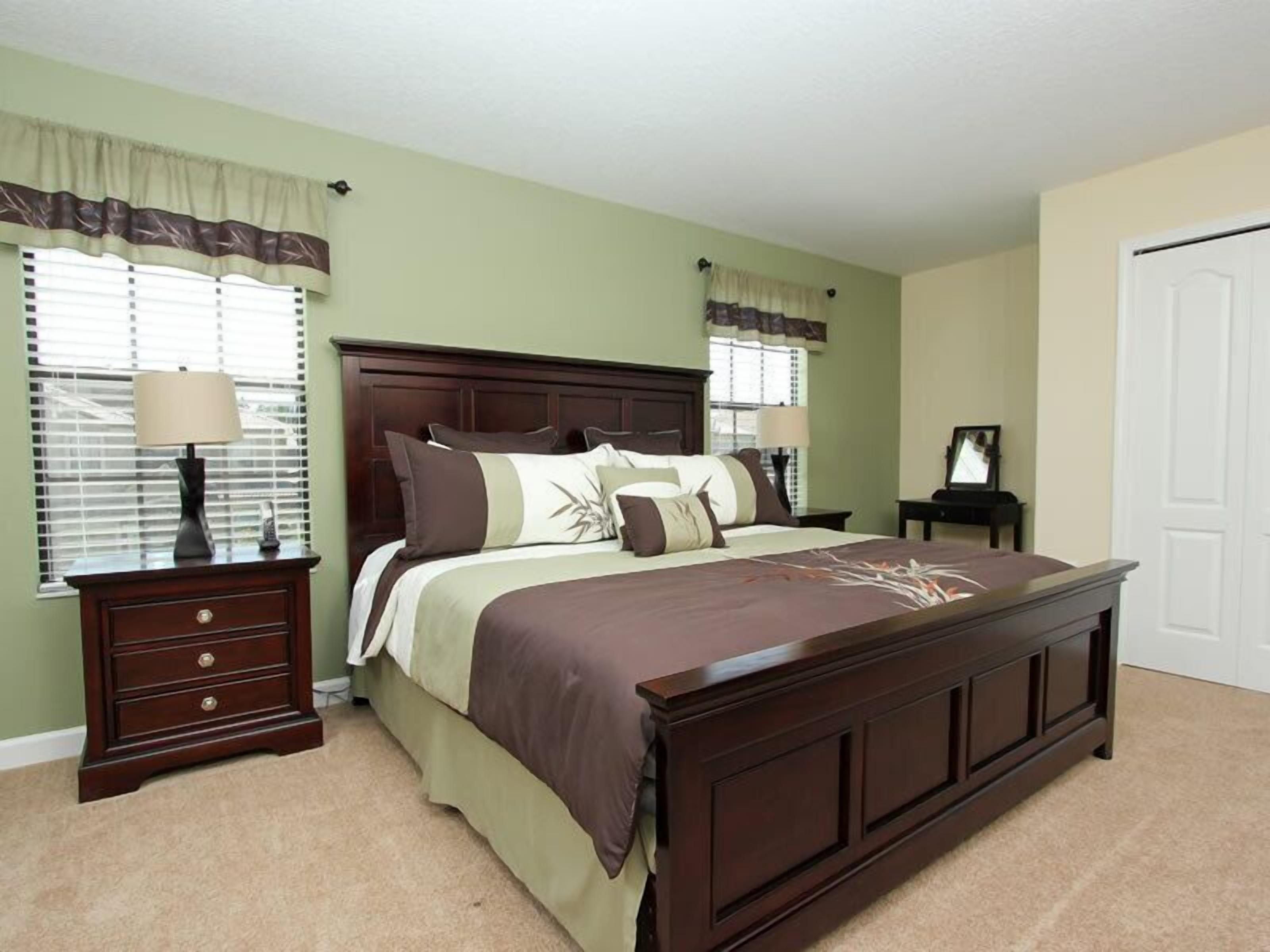 A bedroom with a large bed, two nightstands, a dresser, and a door.