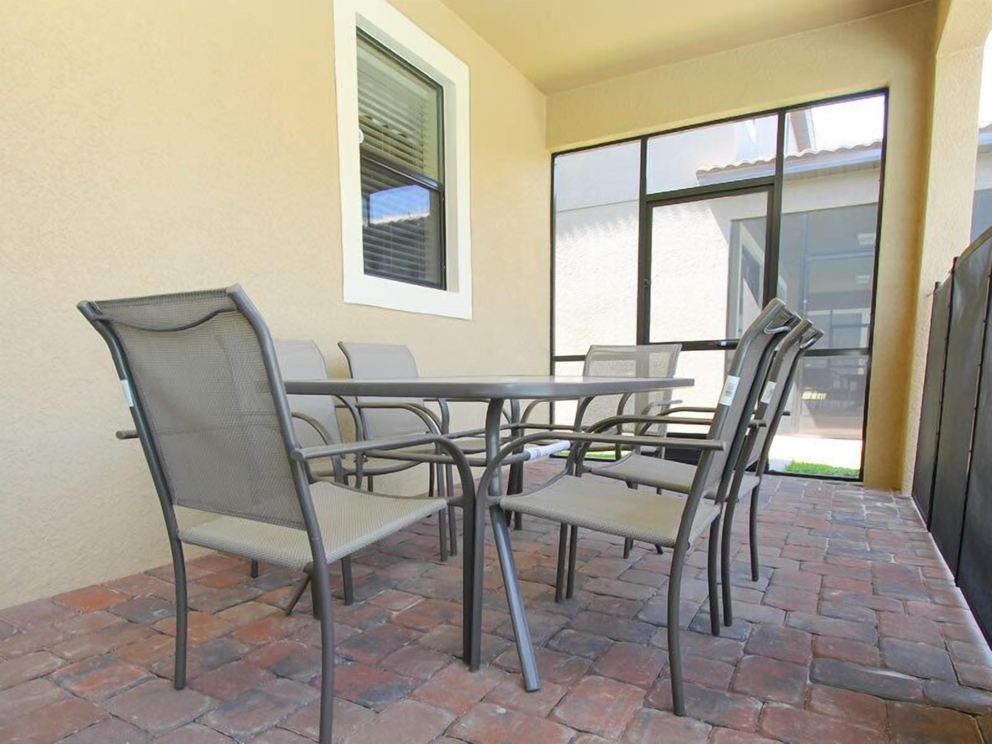 An outdoor patio with a table and chairs, a window, and a view of the street.