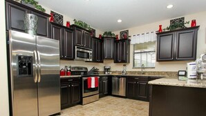 A modern kitchen with dark cabinets, stainless steel appliances, and a granite countertop. - Ov3105 - Champions Gate Resort - 6 Bed 6 Baths Villa (Davenport)