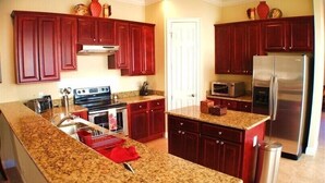 A modern kitchen with granite countertops, stainless steel appliances, and dark red cabinetry. - Ov3057 - Reunion Resort - 4 Bed 3.5 Baths Villa (Kissimmee)
