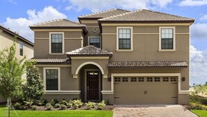 A two-story house with a garage, a front entrance, and a well-maintained lawn. - Ov3060 - Champions Gate Resort - 8 Bed 5 Baths Villa (Davenport)