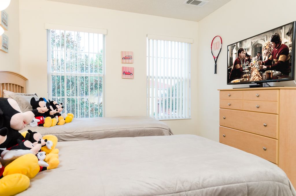 A bedroom with two beds, a TV, and a dresser.