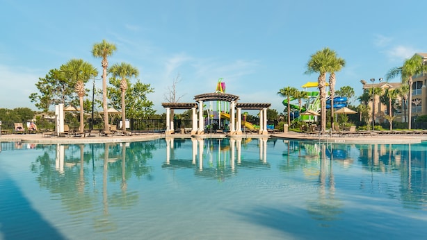 A clear pool with a pavilion, palm trees, and a water slide in the background. - Ov3007 - Windsor Hills Resort - 3 Bed 3 Baths Townhome (Kissimmee)