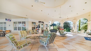 A spacious indoor area with multiple seating arrangements, including striped chairs and a round table. There are signs for a restaurant and a bar, and the area is well-lit with ceiling lights. - Ov3007 - Windsor Hills Resort - 3 Bed 3 Baths Townhome (Kissimmee)