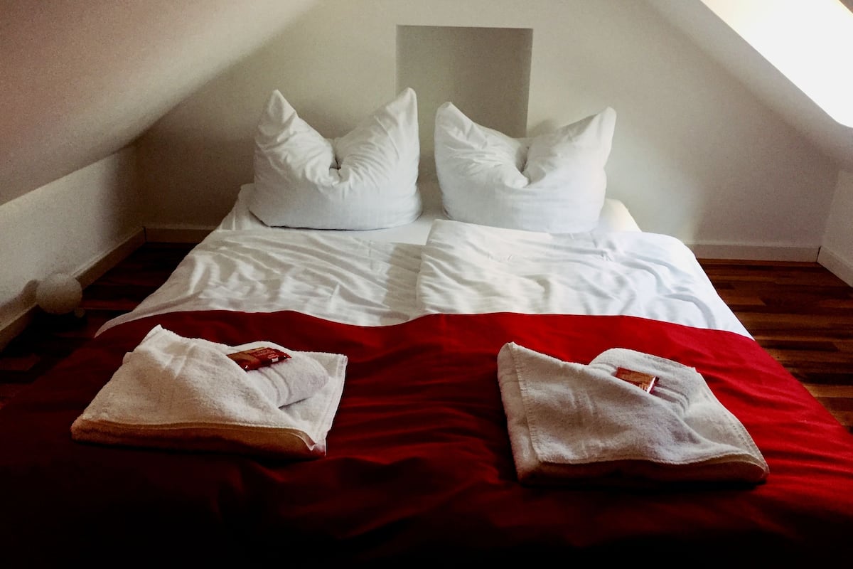 A room with a bed, pillows, and a red blanket.