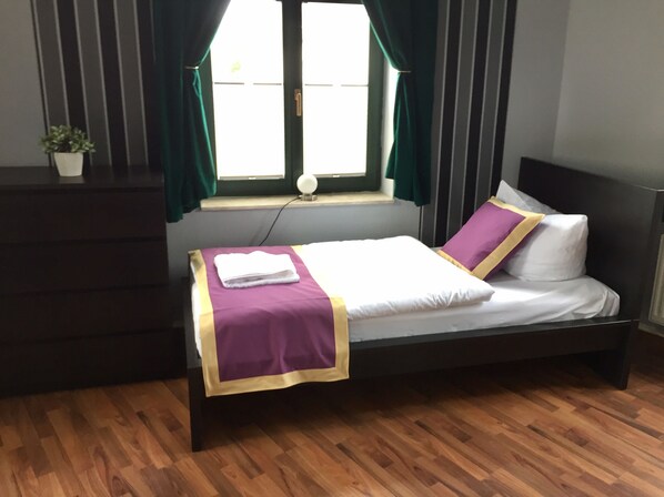 A neatly made bed with a purple and white bedspread, a white pillow, and a matching blanket. - Ferienwohnung Alabama (Lutherstadt Wittenberg)