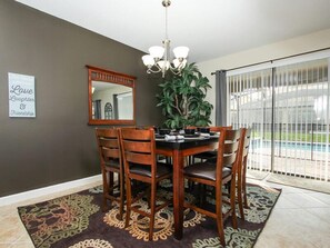 A dining area with a dark wall, a chandelier, a mirror, and a potted plant. - Ov3019 - Champions Gate Resort - 9 Bed 5 Baths Villa (Davenport)