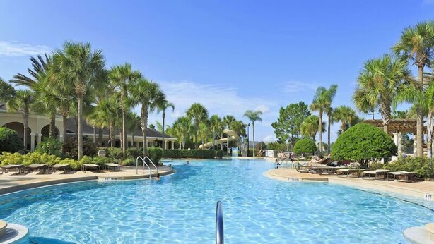 A large outdoor swimming pool surrounded by palm trees and lounge chairs, with a clear blue sky above. - Ov2939 - Windsor Hills Resort - 3 Bed 2 Baths Townhome (Kissimmee)