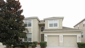 A two-story residential building with a large garage, a covered entryway, and a well-maintained lawn with a tree. - Ov2929 - Windsor Hills Resort - 5 Bed 5 Baths Villa (Kissimmee)