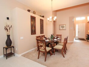 A dining area with a round table, six chairs, a vase with dried plants, and framed artwork on the walls. - Ov2929 - Windsor Hills Resort - 5 Bed 5 Baths Villa (Kissimmee)