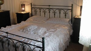 Un lit avec un cadre en métal, une literie blanche et deux tables de chevet avec des lampes.