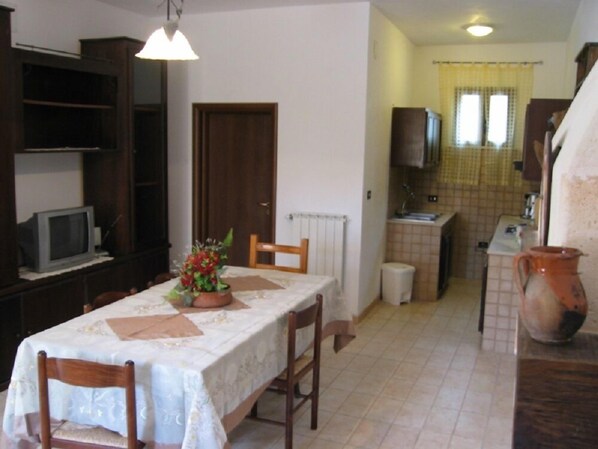 A compact kitchen with a dining area, a television, and a potted plant on the table. - Le Chianche B&B (Oria)
