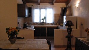 Une cuisine de taille réduite avec un plafond en bois, un évier, une cuisinière et une fenêtre avec des rideaux.
