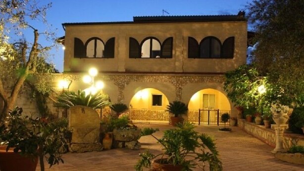 Un bâtiment doté d’une cour intérieure, avec une arche centrale et de nombreuses fenêtres équipées de volets.