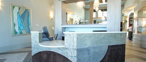 A reception area with a marble counter, a chair, and a large abstract painting on the wall.