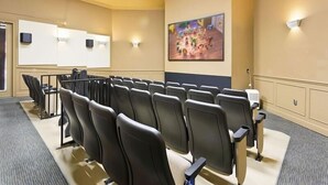 Konferenssihuone, jossa on riveissä tuoleja, projektorikangas ja suuri taulu seinällä.