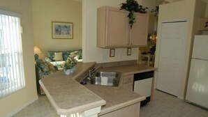 A compact kitchen with a built-in sink, a small island, and a refrigerator. - Ov2942 - Indian Creek - 4 Bed 3 Baths Villa (Kissimmee)