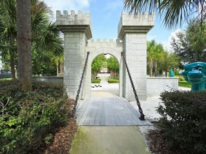 Enter a serene oasis beneath a majestic archway, surrounded by lush greenery and palm trees.