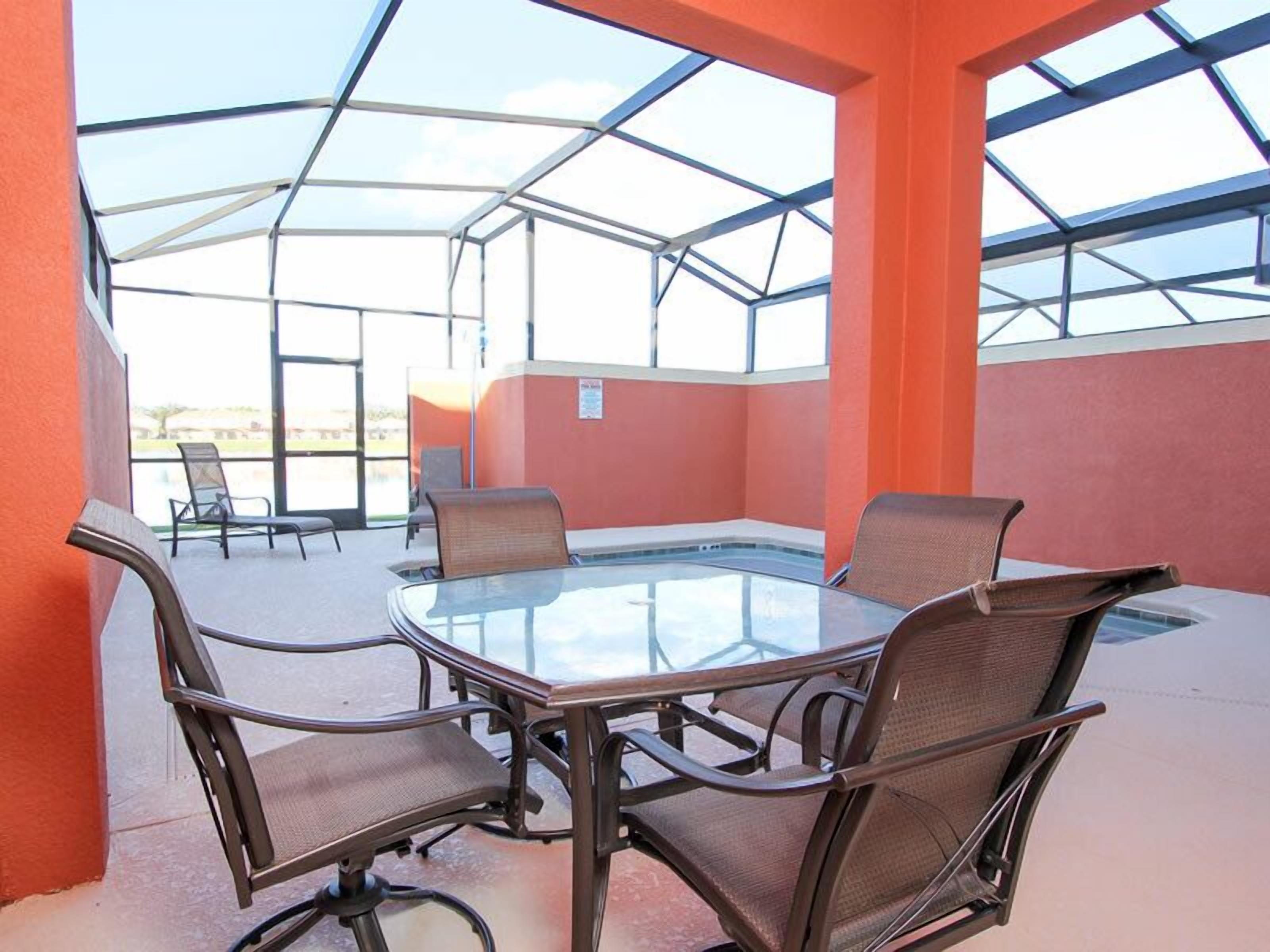 A covered outdoor area with a glass table and four chairs.