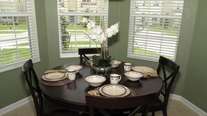 A dining table set with plates, bowls, and a vase of flowers.