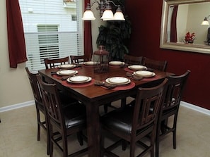 A dining room with a wooden table set for six, surrounded by six chairs.